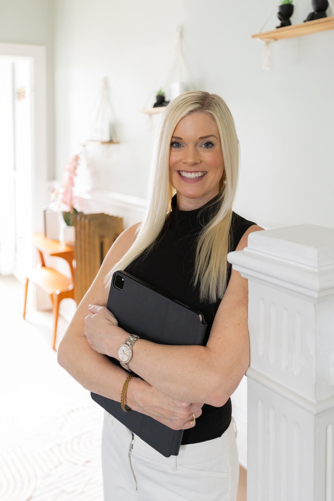Rebecca Entwisle holding a tablet beside a white staircase, smiling